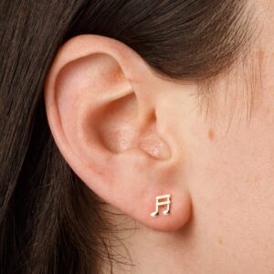 small gold musical note stud earrings worn on ear