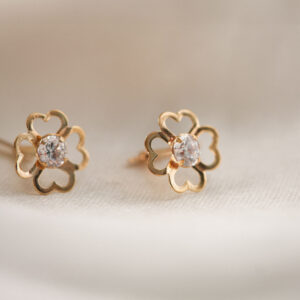 gold clover cz stud earrings in 9ct Yellow Gold with central cubic zirconia, close-up on fabric