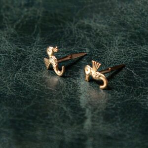 nautical gold seahorse earrings pair on textured background