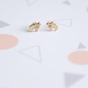 Cow stud earrings staged on flat surface with soft props — gift-style product image